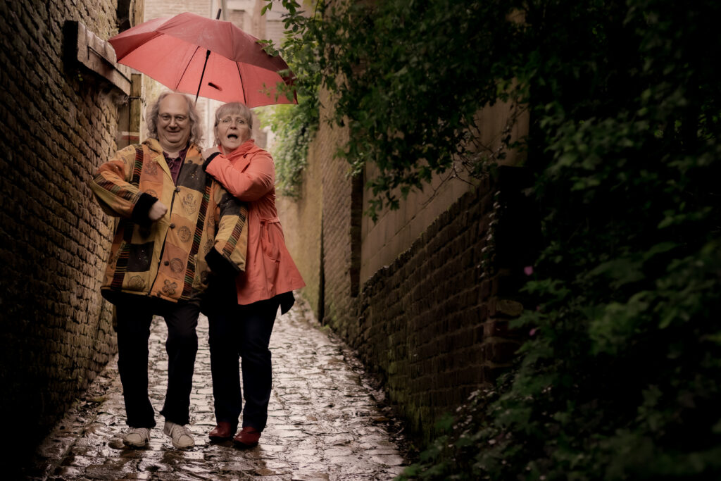 La conteuse et le musicien de Sacrés Marmots sous un parapluie dans une ruelle pavée