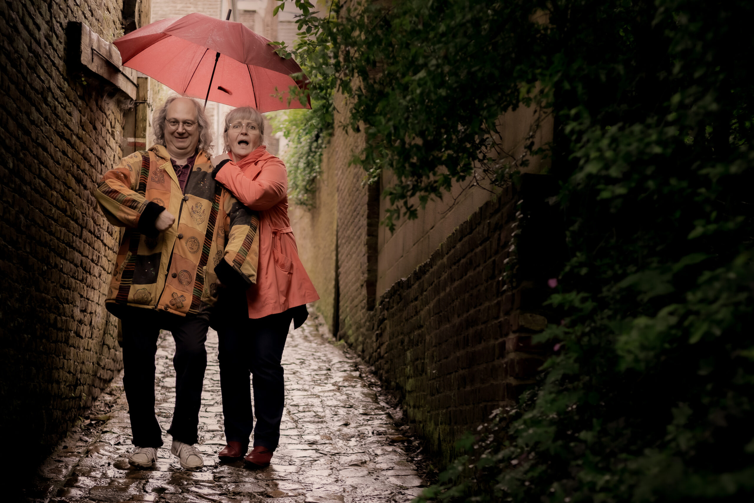 La conteuse et le musicien de Sacrés Marmots sous un parapluie dans une ruelle pavée